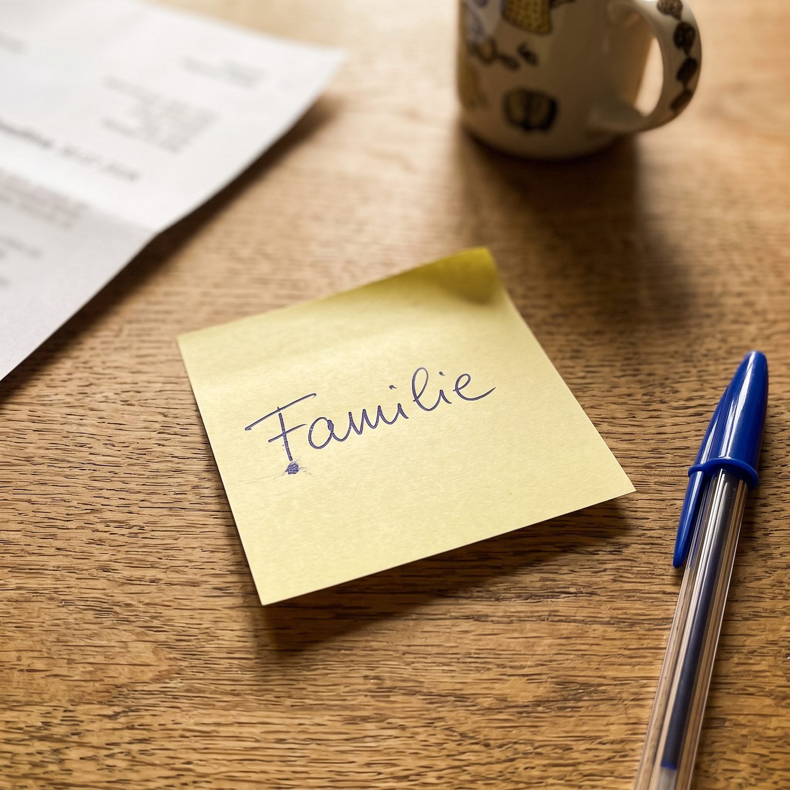 Gelber Post-It-Zettel mit dem handgeschriebenen Wort Familie, daneben ein Kugelschreiber